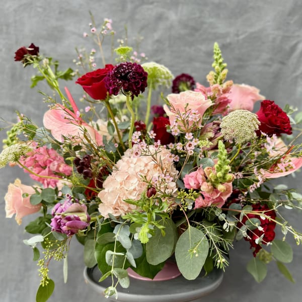 Mixed bouquet of pink, red, and white flowers in a low container