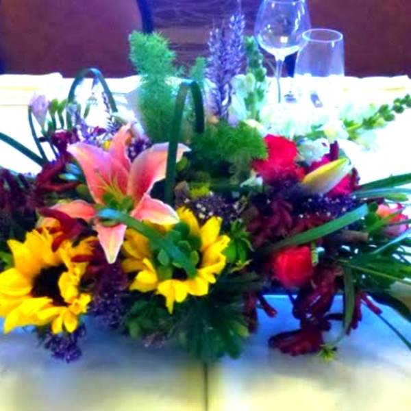 Low centerpiece with lilies, sunflowers, and roses on a banquet table