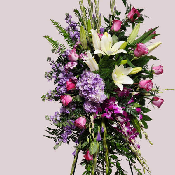Tall standing floral spray with white lilies, pink roses, and purple blooms