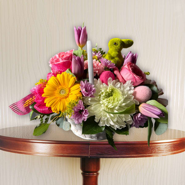 Colorful bouquet with tulips, daisies, and a green bunny figurine in a white container