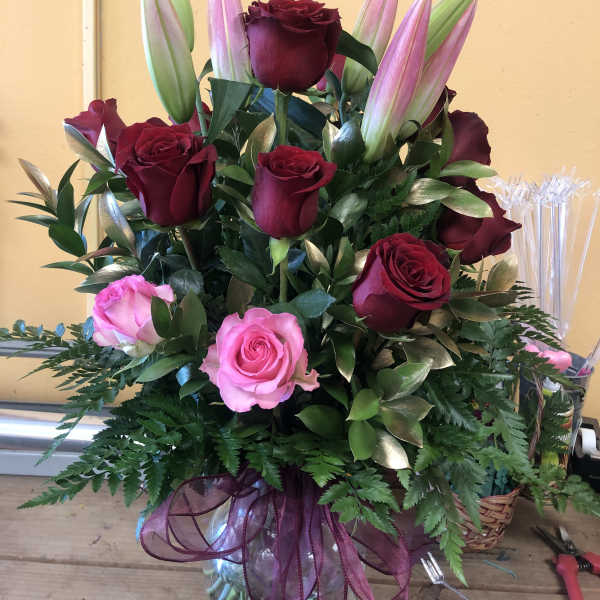 Bouquet of red and pink roses with unopened lilies in a vase