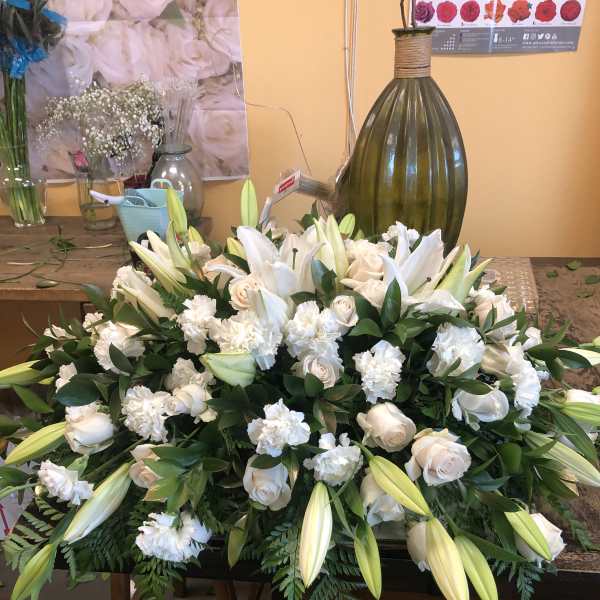 Large white floral arrangement with lilies and roses on a table