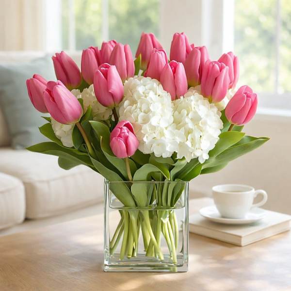 Pink tulips and white hydrangeas arranged in a clear glass vase.