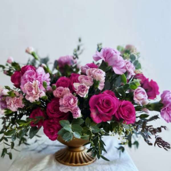 Pink roses and carnations in a gold pedestal vase