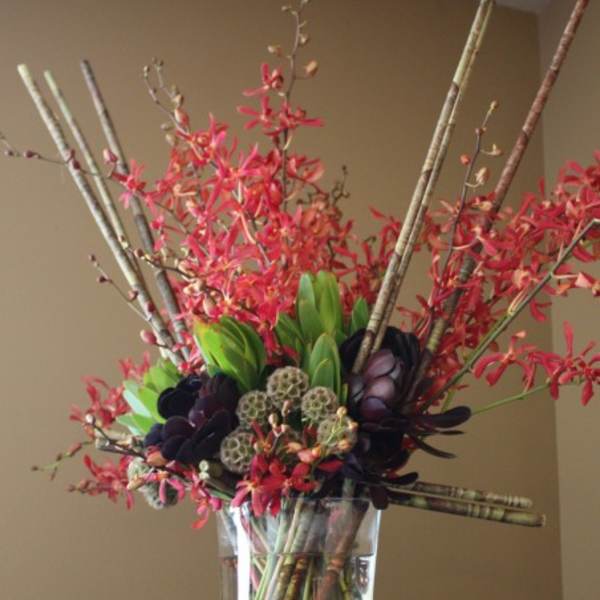 Tall floral arrangement with red blooms in a clear glass vase