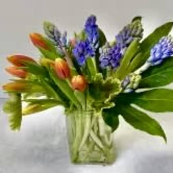 Bouquet of orange tulips and purple hyacinths in a clear glass vase
