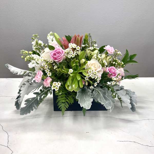 Pink and white floral arrangement in a rectangular container