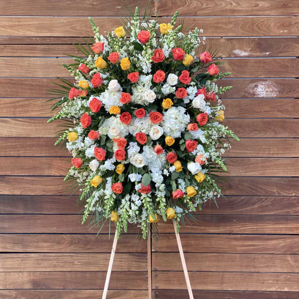 Large standing floral spray of multicolored roses and white blooms on an easel