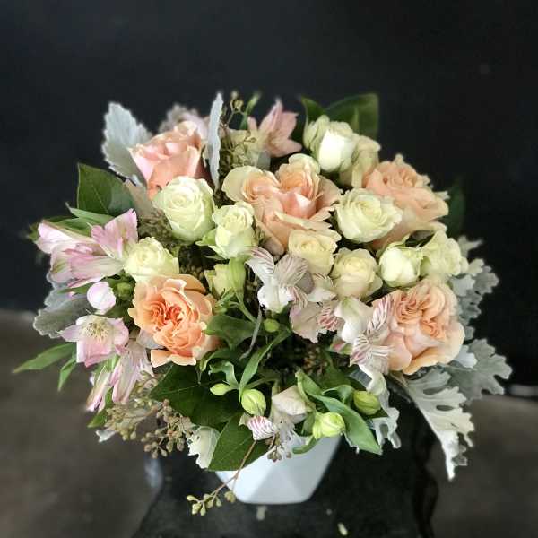 Peach and cream rose bouquet in a white vase