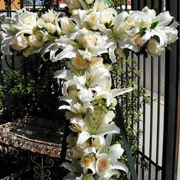 White lilies and cream roses arranged on a tall cross display