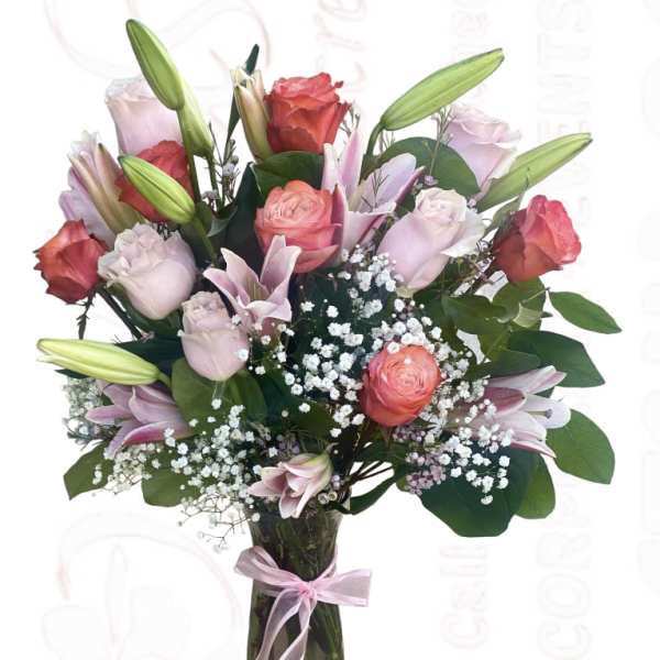 Bouquet of pink roses and lilies in a glass vase with a ribbon