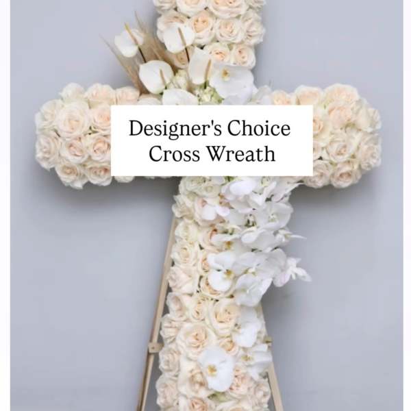 White floral cross wreath on a stand with pale roses and orchids