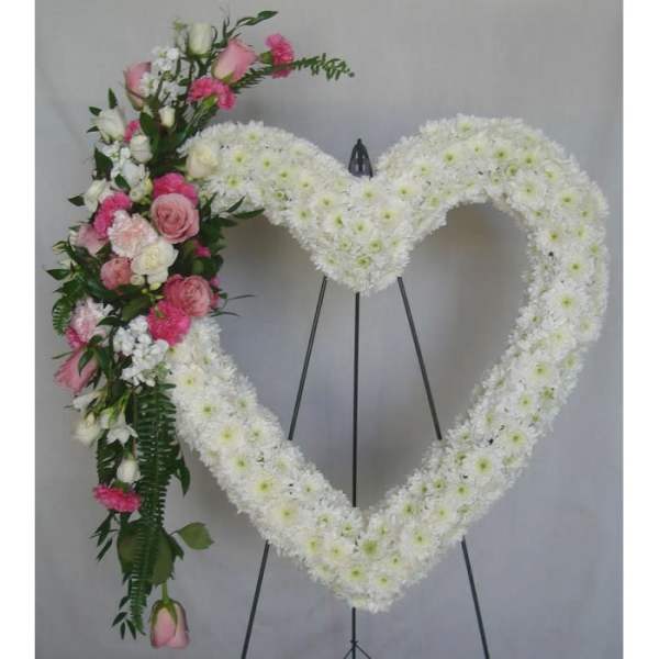 Heart-shaped white floral funeral wreath with pink roses and carnations