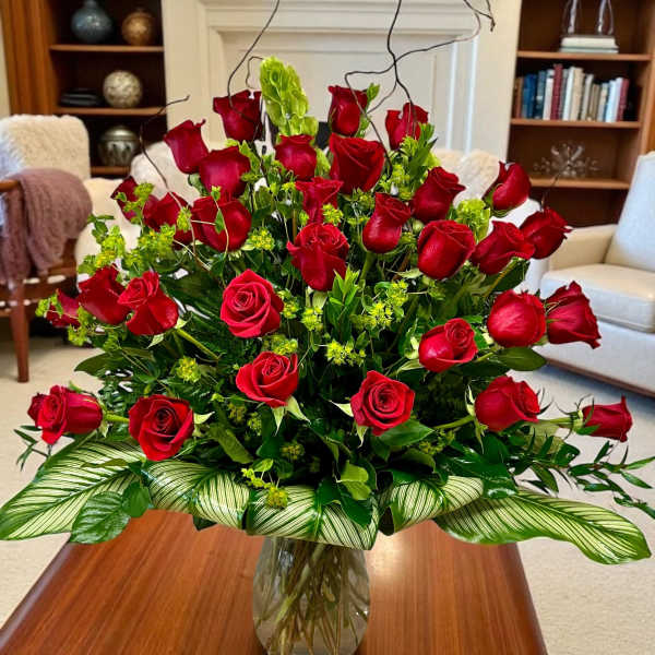 Large arrangement of red roses with green accents in a clear glass vase