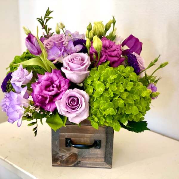 Purple and green floral arrangement in a wooden box