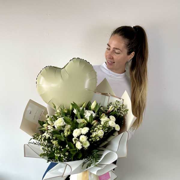 Woman holding a large white flower bouquet with a heart balloon