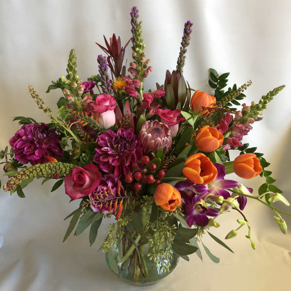 Mixed bouquet of pink, orange, and purple flowers in a glass vase