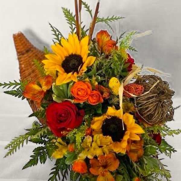 Mixed bouquet with sunflowers, roses, and orange blooms in a woven basket