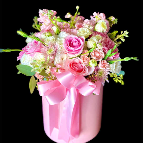 Pink and white mixed flower arrangement in a pink box with a ribbon