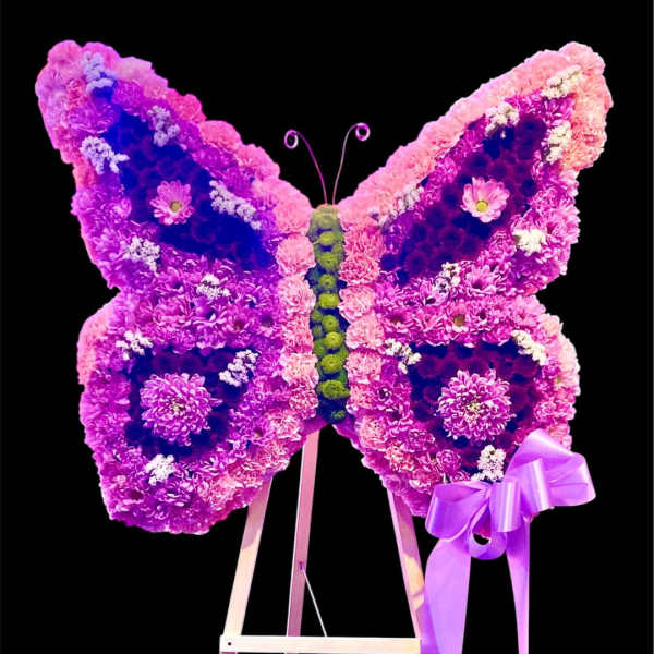 Butterfly-shaped floral display in pink and purple on an easel