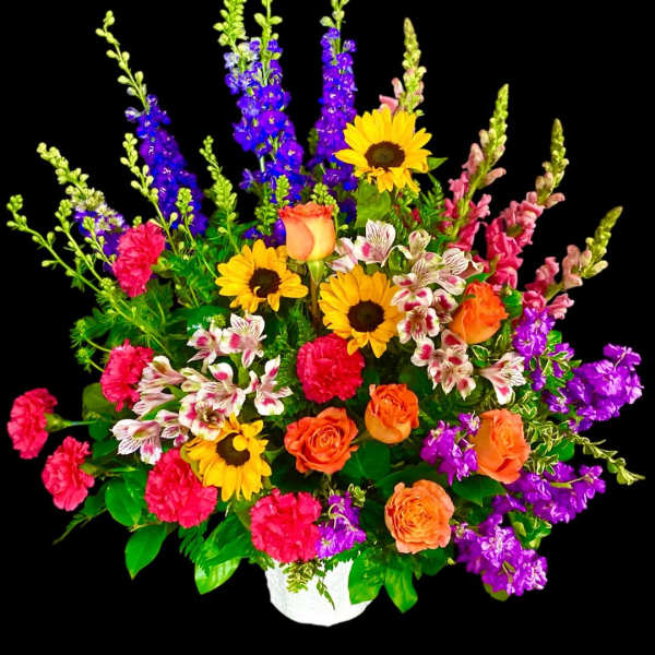 Colorful mixed flower arrangement in a white vase with sunflowers and roses