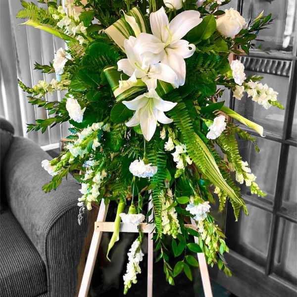 Tall white floral spray with lilies and roses on an easel