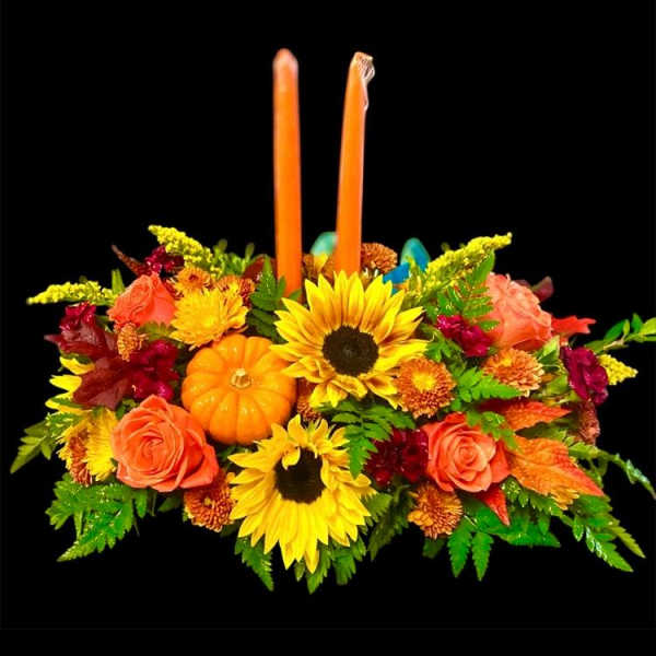 Autumn floral centerpiece with two orange candles and a small pumpkin