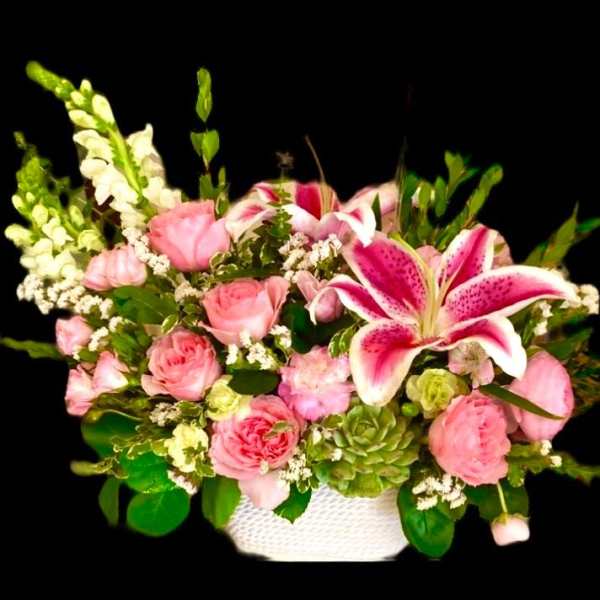 Pink roses and lilies arranged in a white basket