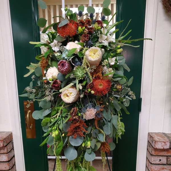 Large floral wreath with mixed blooms and greenery on a stand