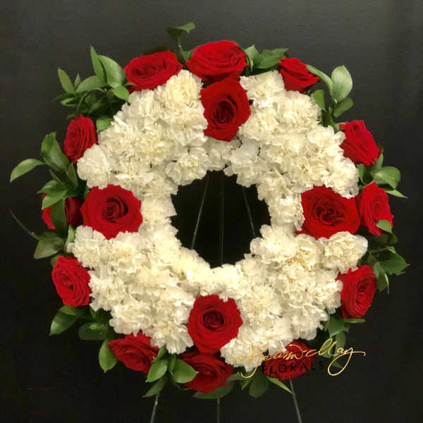 Circular wreath of red roses and white carnations on a black stand