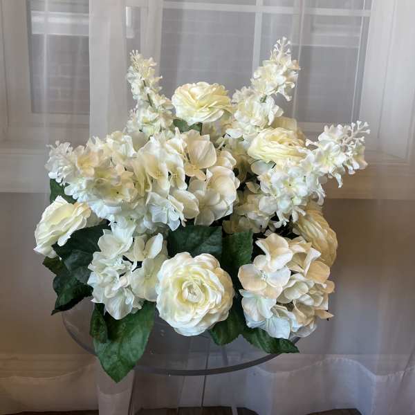 White floral arrangement with hydrangeas and roses in a clear vase