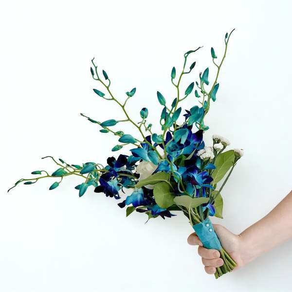 Handheld bouquet of blue orchids and white filler flowers
