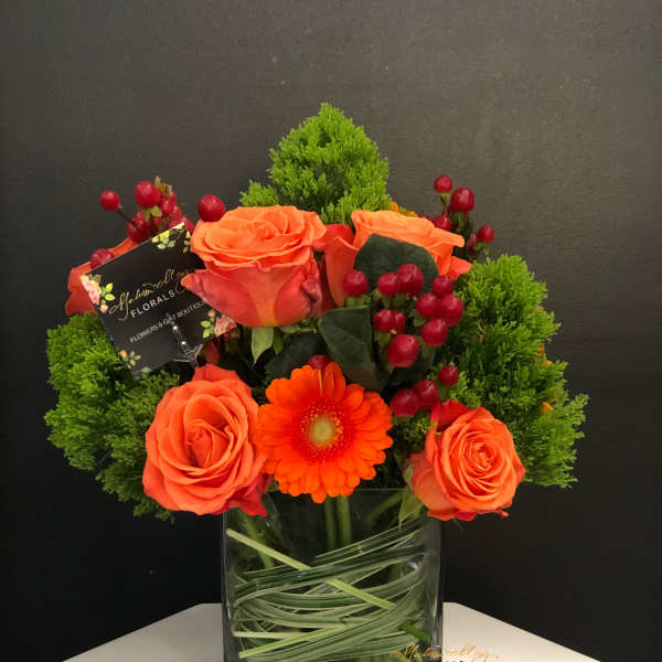 Orange roses and a gerbera daisy in a glass vase