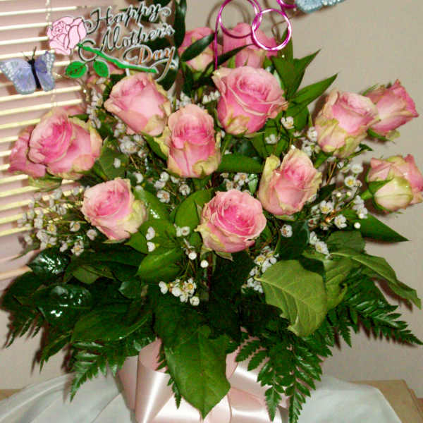Pink roses arranged in a vase with a Mother's Day topper and butterfly picks