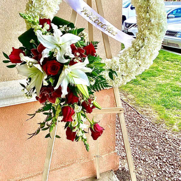 Heart-shaped floral wreath with red roses and white lilies on an easel