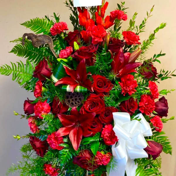 Large red floral standing spray with a white ribbon on an easel