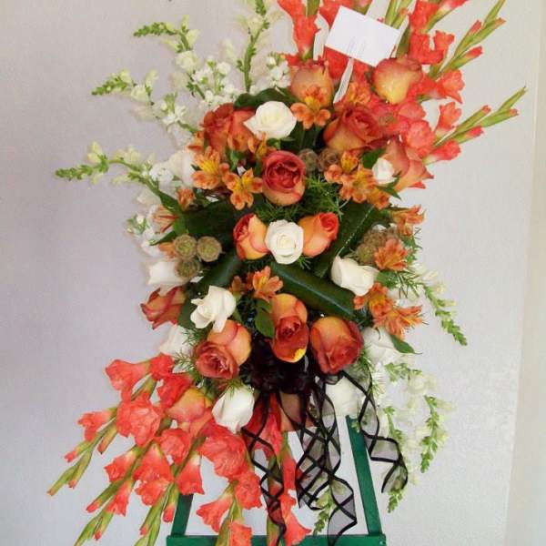 Tall floral standing spray with orange and white roses and red gladiolus