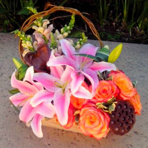 Pink lilies and orange roses in a basket with a woven handle