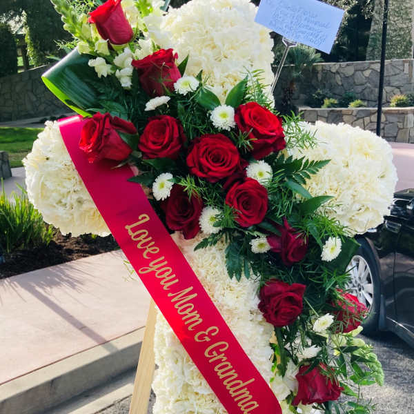 Standing floral cross with red roses and white flowers on an easel