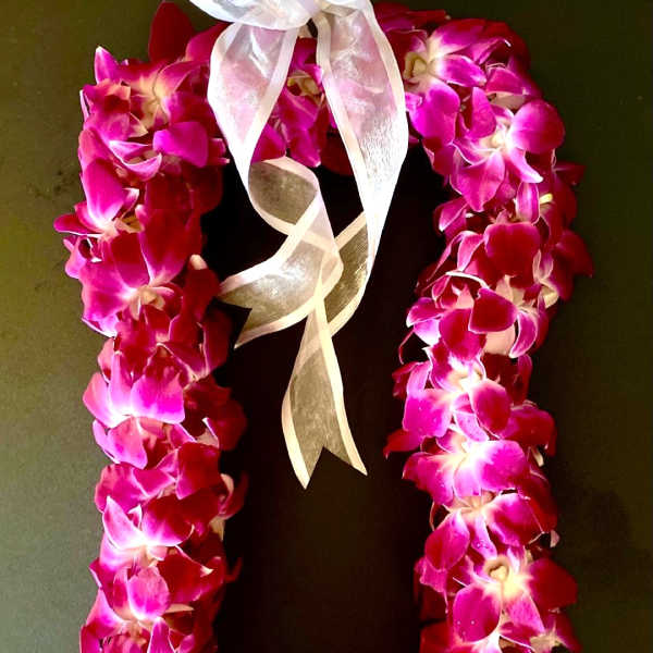 Pink orchid lei with a white ribbon bow
