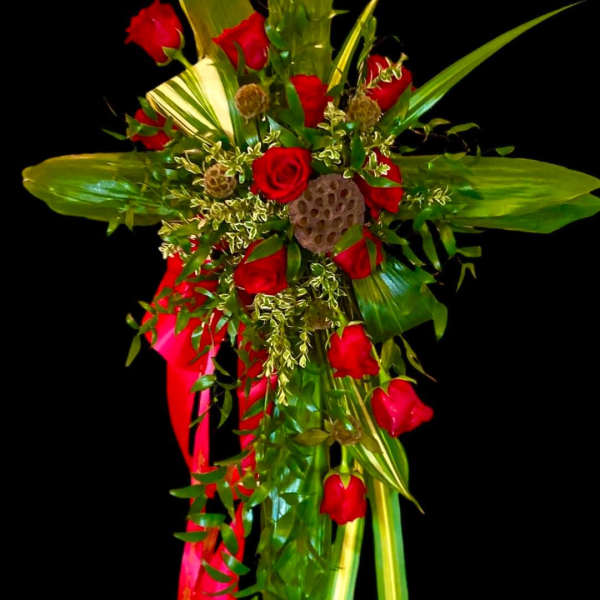 Red roses and tropical greenery arranged with a red ribbon on a black background