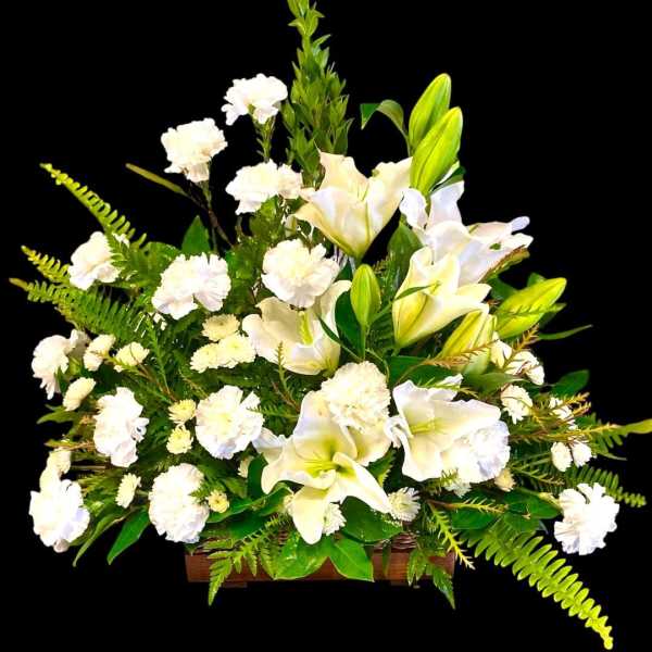 White lilies and carnations arranged in a wooden container