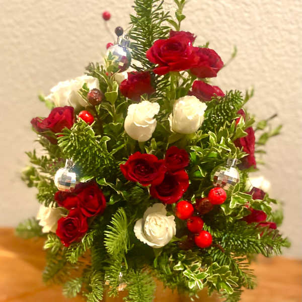 Red and white rose arrangement with holiday ornaments in a vase