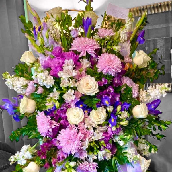Large bouquet of pink, purple, and white flowers with ribbon tails