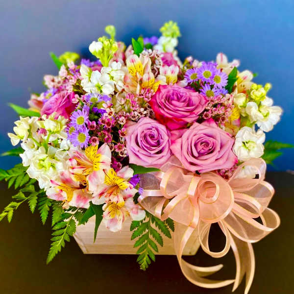 Pink and lavender rose bouquet in a wooden box with a ribbon bow
