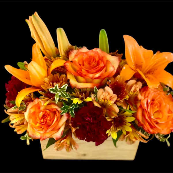 Orange roses and lilies arranged in a rectangular wooden container