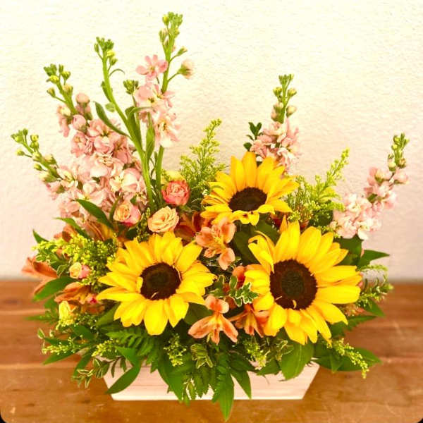 Sunflower and pink mixed flower arrangement in a white container