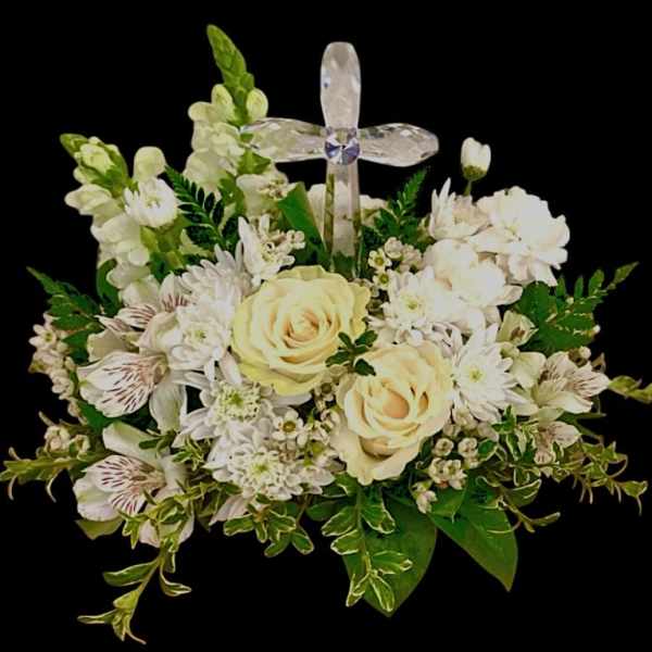White floral arrangement with cream roses and a clear cross pick