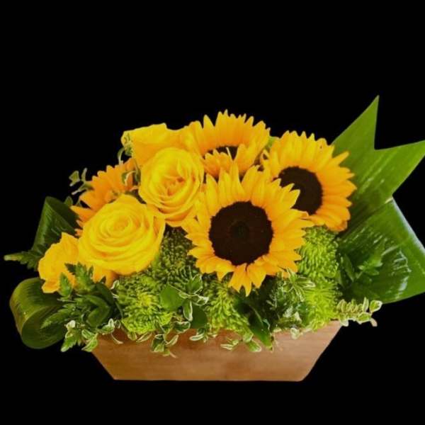Yellow roses and sunflowers in a low rectangular container