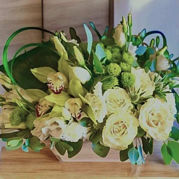 Cream roses and pale orchids in a low rectangular arrangement